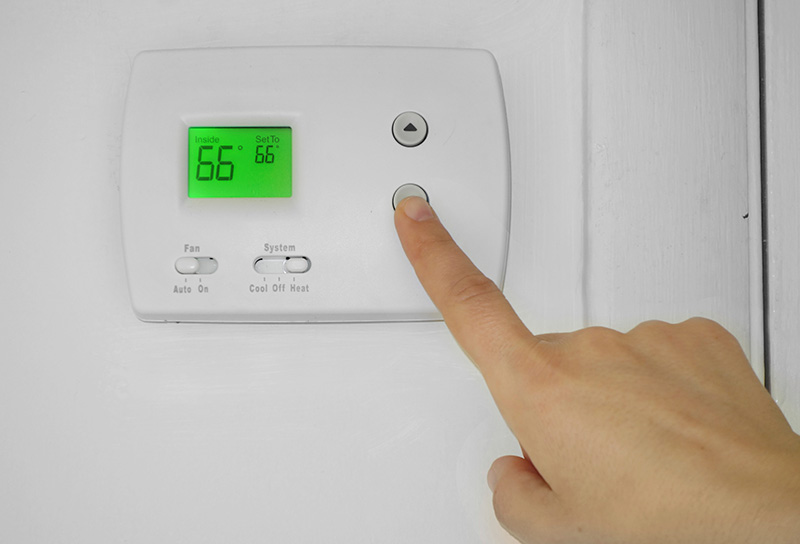 Person adjusting a wall thermostat temperature